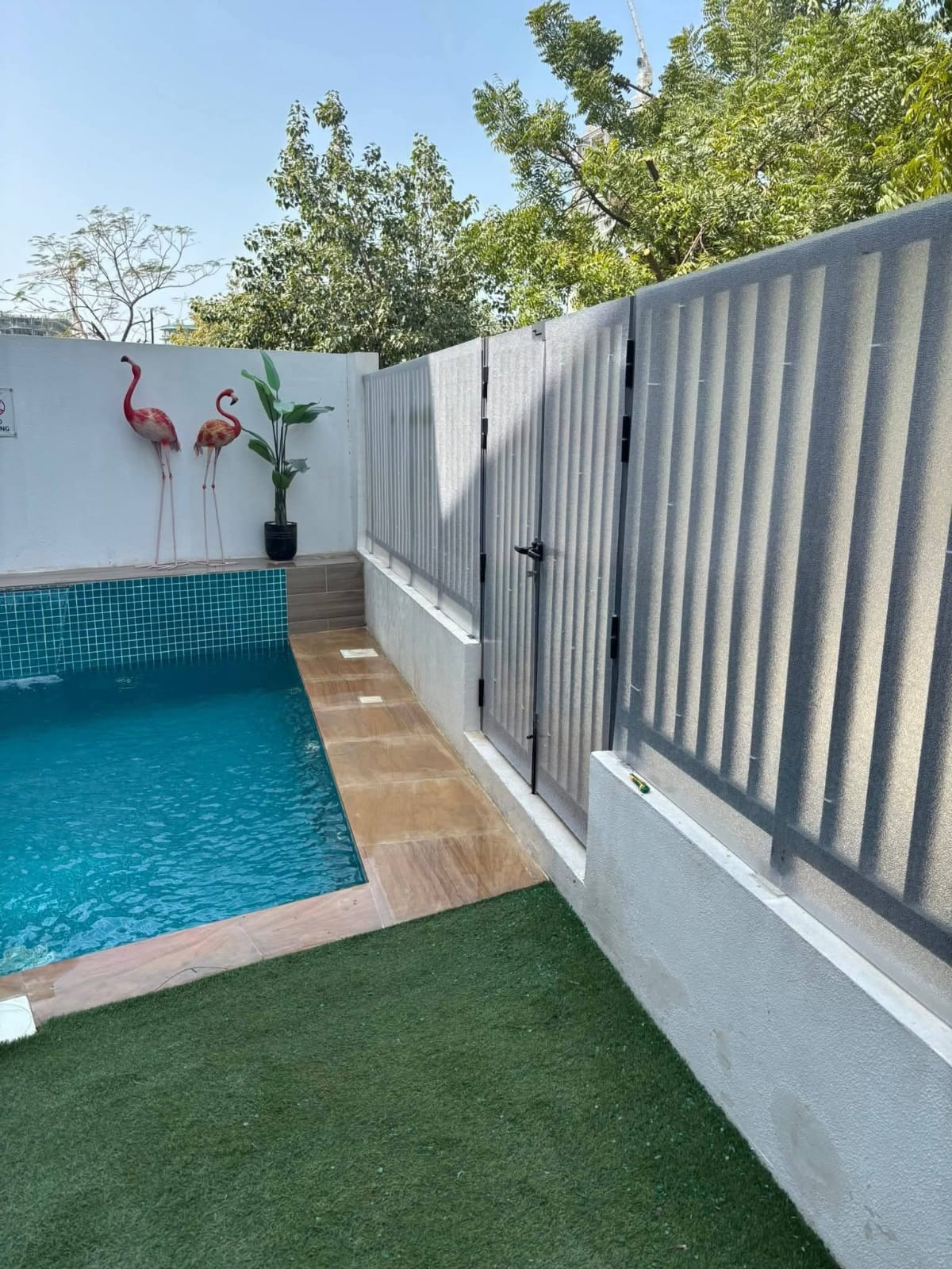 Small villa pool with mosaic tile, flamingo ornaments and turf