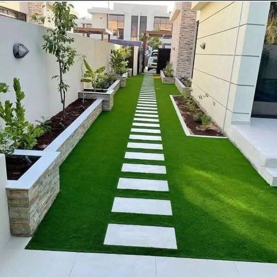 Long turf courtyard with a white paver path and raised planters