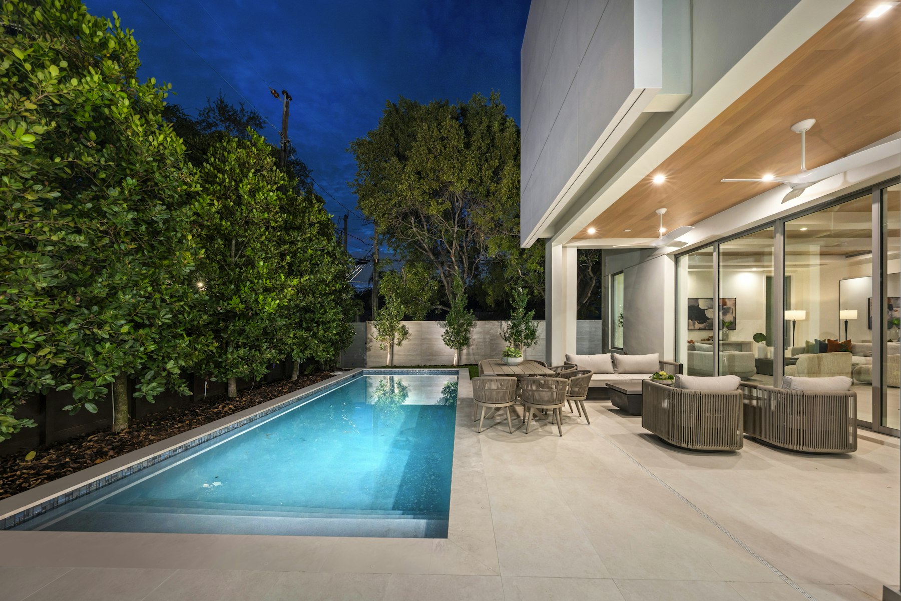 Pool and lit living space at dusk